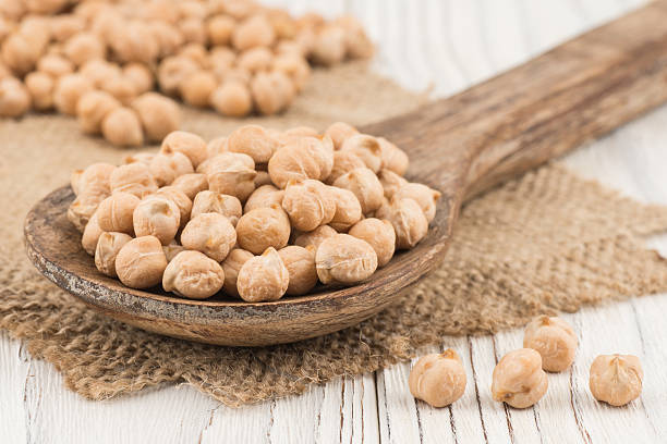 istock Chickpeas in a wooden spoon and old white wooden table. 605782402