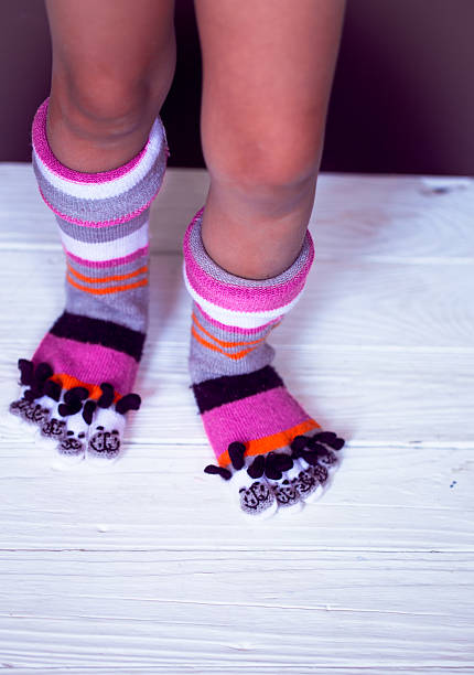 istock Baby feet in warm, long multicolored socks with toes 605785826