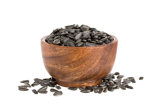 istock Black sunflower seeds in bowl isolated on white background 605788040