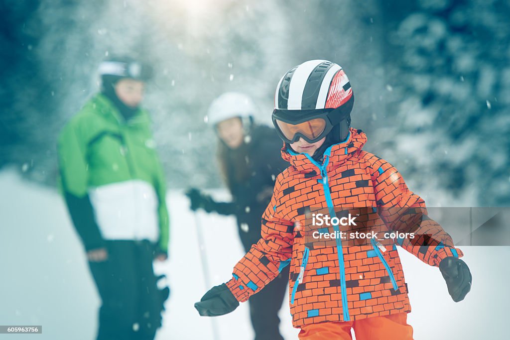 little boy skiing selective focus on little boy in winter time skying, his mother and father defocused in background.winter day Skiing Stock Photo