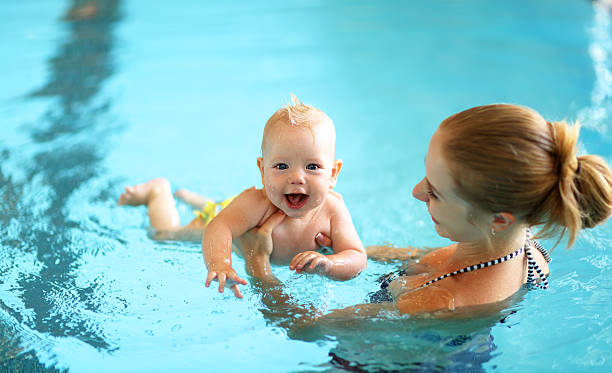 istock mother teaching baby swimming pool 605971184
