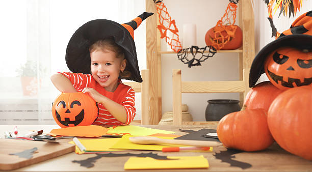 istock happy laughing child girl in a witches hat eats sweets 605976314