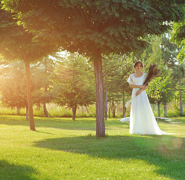 Bride holding peacock bridal bouquet in a magnificent garden.