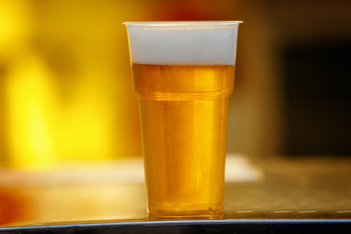 A refreshing pint of cold beer on a wood surface with white background.