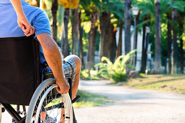 Man on wheelchair in a park Man on wheelchair in a park sclerosis stock pictures, royalty-free photos & images