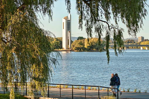 Canberra, Australia, 10 March 2010. People enjoy a peaceful walk in Commonwealth park along Burley Griffin lake. The Carillon appears amongst the trees.