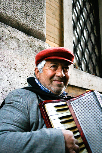 Rome, Italy - March 25, 2008: A street musician in a red cap plays an old accordion (close-up portrait).