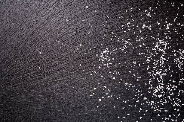 istock sprinkled sea salt over black slate stone background, top view 605990010