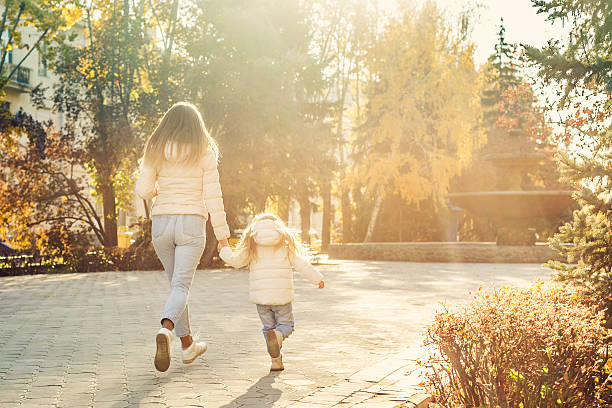 istock Mother and daughter running to the setting sun. 605990196