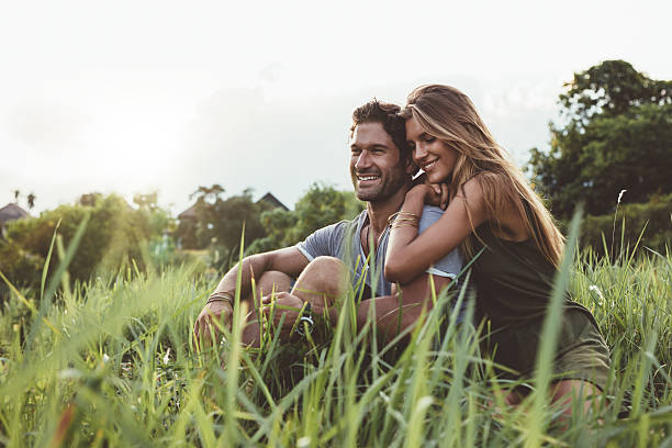 istock Young happy lovers sitting on meadow 605990254