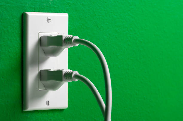 istock Electrical cords plugged white outlet on a green wall 605990728