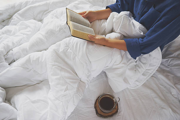 Girl reading book and drinking coffee on the bed