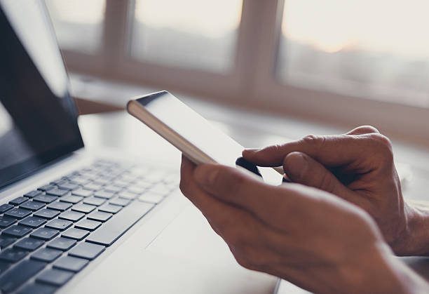 Using laptop and smart phone Male hands using smart phone and laptop computer dialing stock pictures, royalty-free photos & images