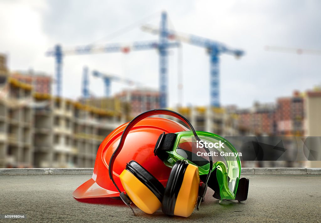 Red helmet and earphones on buildings background Red helmet and earphones on buildings background closeup Occupational Safety And Health Stock Photo
