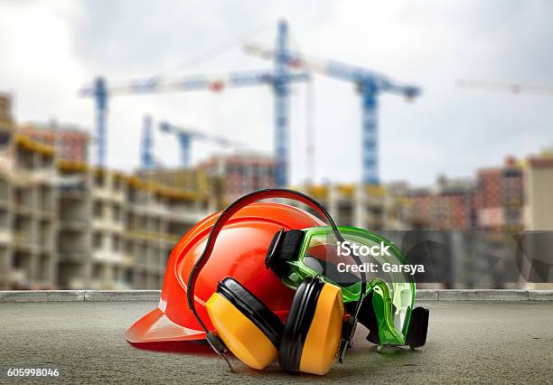 Red Helmet And Earphones On Buildings Background Stock Photo - Download Image Now - Occupational Safety And Health, Equipment, Construction Industry