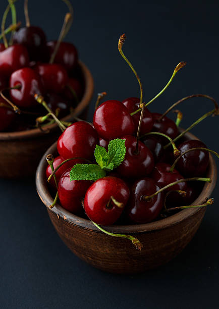 istock Ripe cherries in a clay bowl on black background 605998760