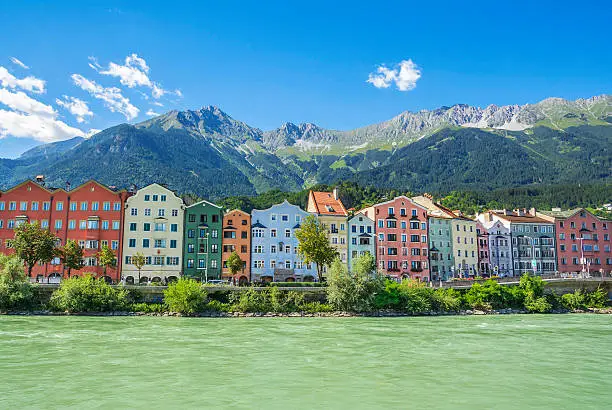 Innsbruck, capital of Tirol, Austria. Building facade with Inn River in front and Alps mountains behind.