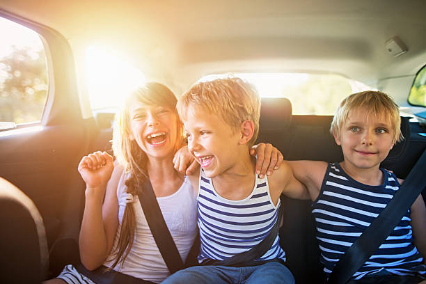 Kids having fun in car on a road trip Three kids laughing in car on a road trip. Kids are aged 10 and 7. The kids are laughing and embracing, Sunny summer day. brother photos stock pictures, royalty-free photos & images