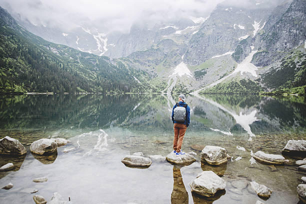 istock man relaxing on the lake and mountains sunny landscape 606006324