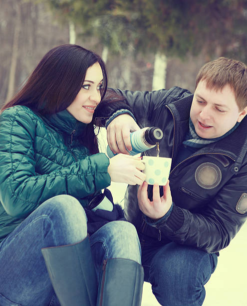 istock Happy couple having fun in winter park drinking hot tea 606009224