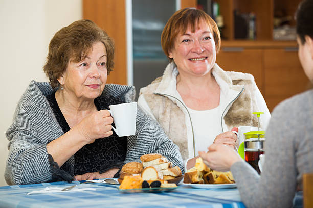 istock Young female and mature women drinking tea and talking 606012362
