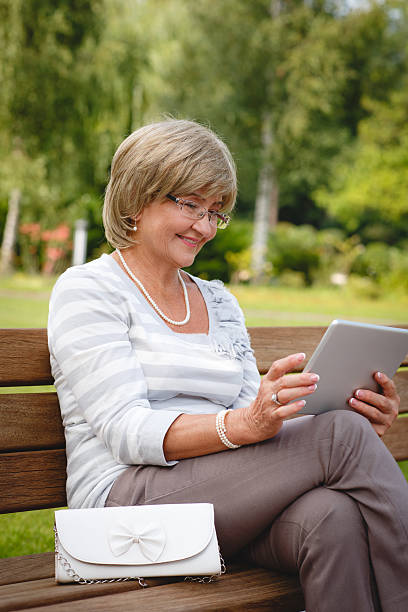 istock Attractive mature woman using digital tablet in a park 606013054