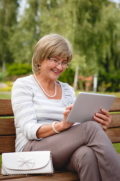 istock Attractive mature woman using digital tablet in a park 606013198