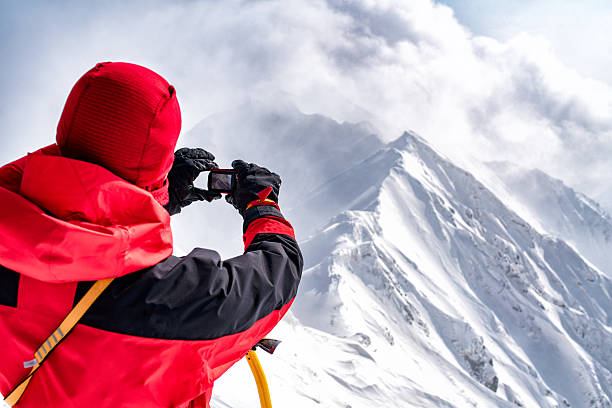 An Ice climber takes a photograph atop the summit he just conquered. Tottori, Japan. February 2016.