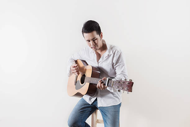istock asia man sit on a chair and play guitar 606199190