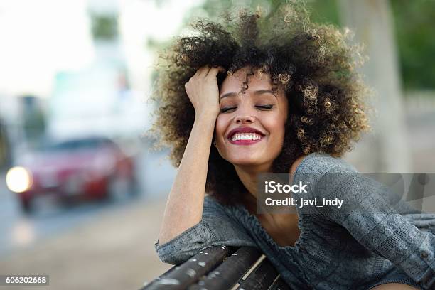 Young Black Woman With Afro Hairstyle Smiling In Urban Backgroun Stock Photo - Download Image Now