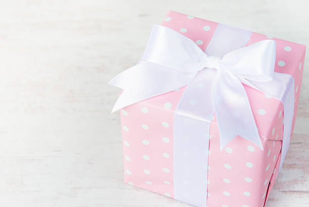 istock Gift box wrapped in pink dotted paper and white bow 606203878