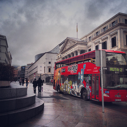 Madrid, Spain - December 25, 2013: Tour Bus on rainy Madrid streets, Spain. People exploring city during winter holidays. 