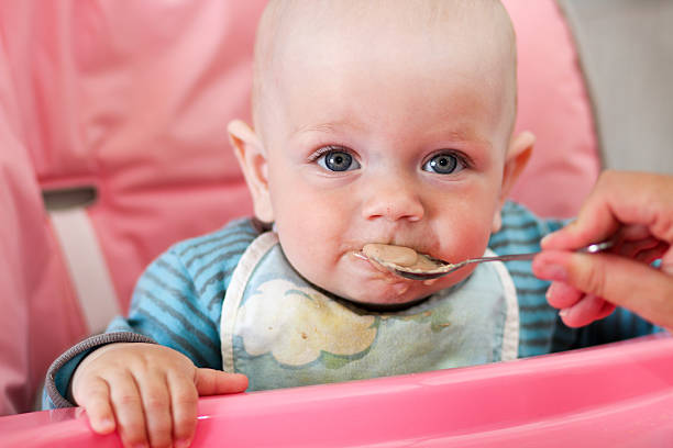 istock Beautiful baby eats porridge from mom's hand. He is 606207384