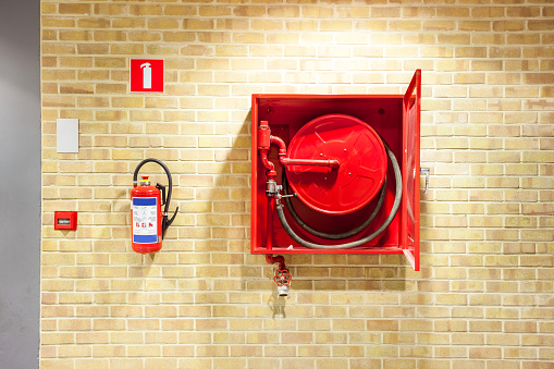 an fire hose hanging on the wall and powder extinguisheran fire hose hanging on the wall and powder extinguisher