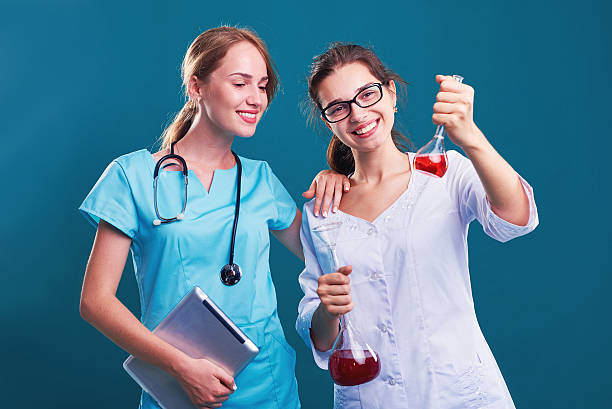 duas cientistas mulheres trabalhando em laboratório com frascos - healthcare and medicine digital tablet medical exam doctor - fotografias e filmes do acervo