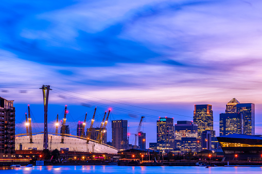 Royal Victoria Dock in London at sunset with illuminated cityscape including Canary Wharf