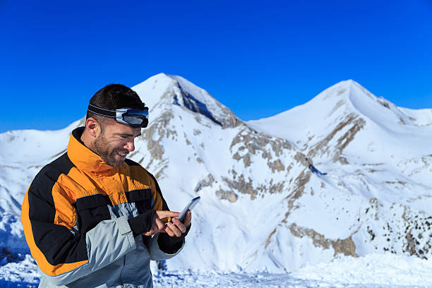 istock Young man using smart phone on top snow mountain 606217392