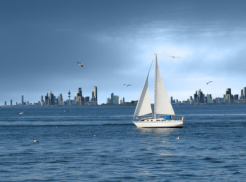 A white boat sailing on the gulf sea showing beautiful Kuwait cityscape in the background