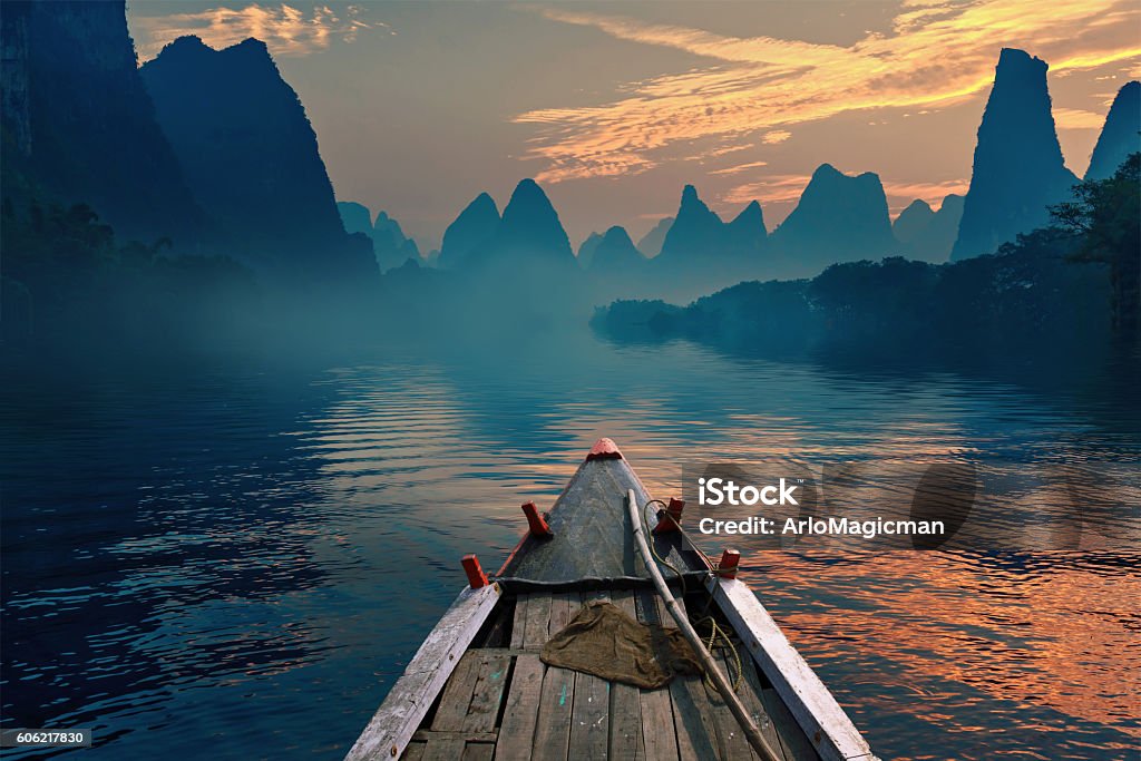 Boat riding in a river A boat riding in a river during sunset next to a beautiful mountain Landscape - Scenery Stock Photo