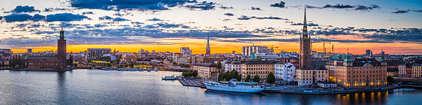 Stockholm sunset spires City Hall illuminated waterfront cityscape panorama Sweden Warm summer sunset skies framing the landmarks of Stockholm, Sweden's vibrant capital city, from the iconic bell tower of City Hall to the colourful lights and iconic historic townhouses, restaurants and bars of Gamla Stan. sodermalm photos stock pictures, royalty-free photos & images