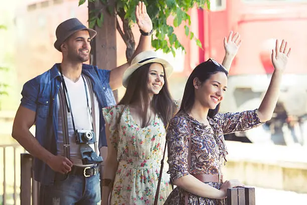 Young old-fashined people greeting a friends on the trainstation and smiling.