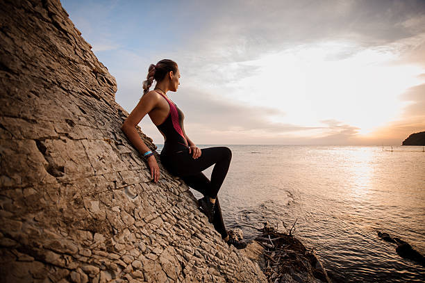 istock Female rock climber watching sunset over sea 606223542