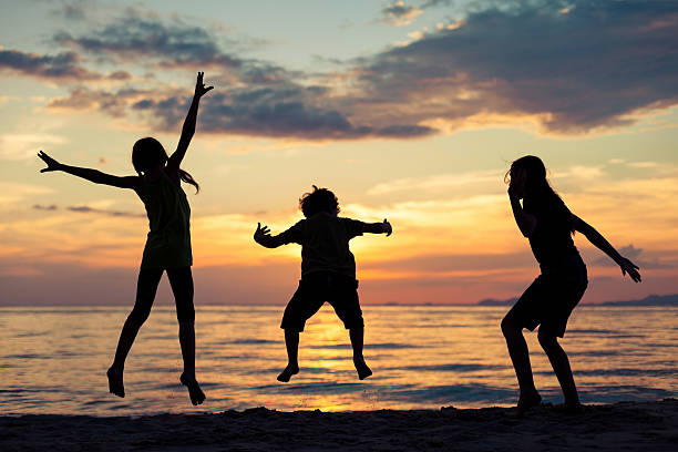 istock Happy children playing on the beach at the sunset time. 606228022