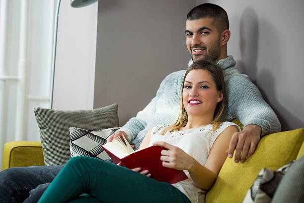istock Relaxed young couple reading book on couch at home 606228922