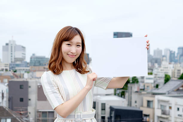 笑顔の若い女性を示すブランクサインボードを - bulletin board ストックフォトと画像
