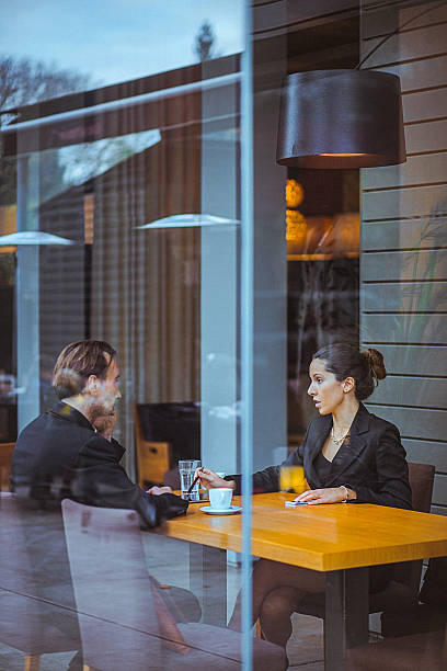 Businesswoman and man having a conversation in modern office space. They are looking at laptop. The man has a beard and both are well dressed. Copy space has been left.