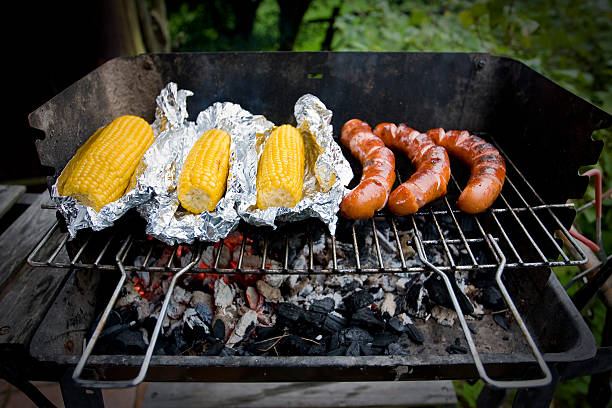 Man cooking corn on barbecue grill outdoors close up