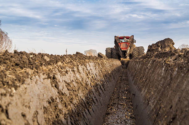 tractor con ditcher de doble rueda excavando canal de drenaje. - deep of field fotografías e imágenes de stock