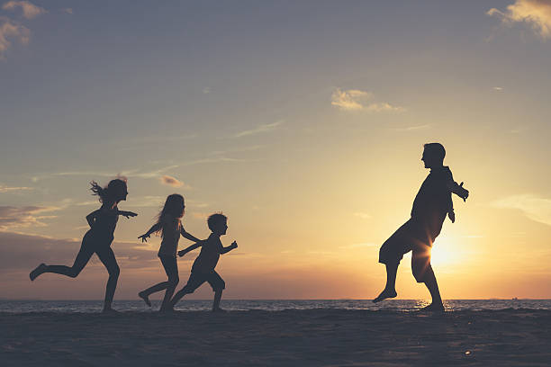 istock Father and children playing on the beach at the sunset. 606238712
