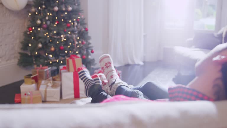 Affectionate couple relaxing in socks with feet up on sofa facing Christmas tree